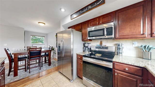 10759 Clermont St, Thornton, CO 80233 - kitchen featuring stainless steel appliances, tasteful backsplash, light stone counters, and light tile patterned floors