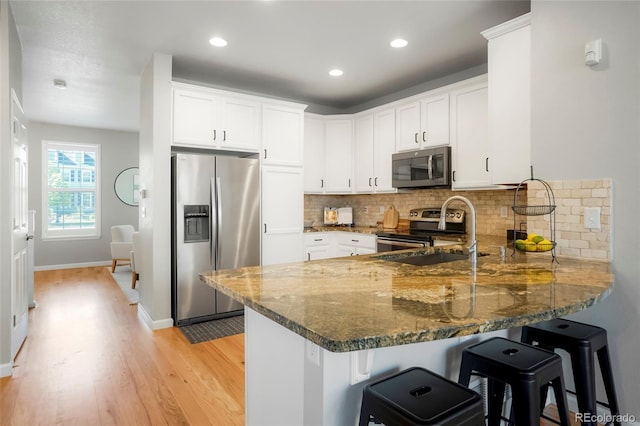 8427 E 35th Ave, Denver, CO 80238 - kitchen featuring appliances with stainless steel finishes, a peninsula, dark stone countertops, tasteful backsplash, and recessed lighting