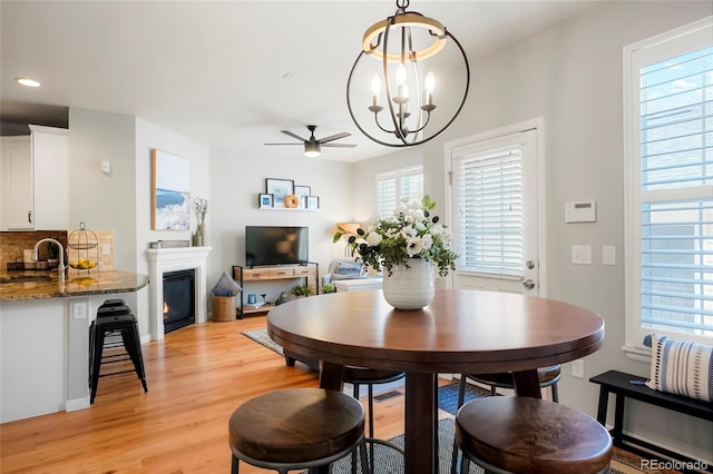 8427 E 35th Ave, Denver, CO 80238 - dining space with light wood finished floors, a ceiling fan, a chandelier, a glass covered fireplace, and recessed lighting