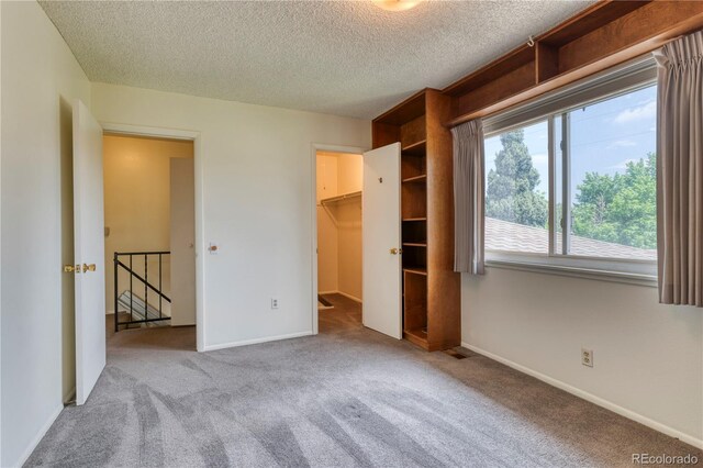 3351 S Field St Unit 191, Lakewood, CO 80227 - unfurnished bedroom with carpet flooring, a textured ceiling, baseboards, and a walk in closet