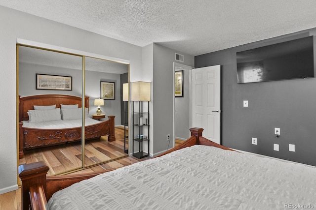 bedroom with wood finished floors, baseboards, a closet, and a textured ceiling