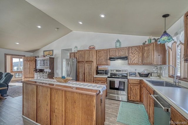 kitchen with pendant lighting, vaulted ceiling, stainless steel appliances, sink, and light wood-type flooring