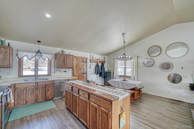 kitchen with decorative light fixtures, vaulted ceiling, light wood-type flooring, and stainless steel appliances