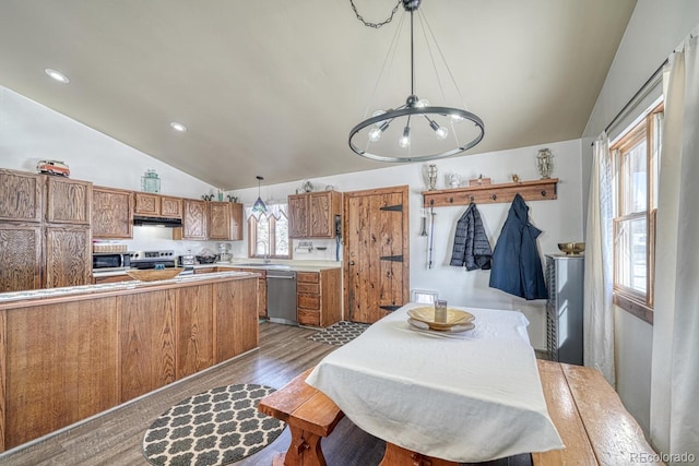 dining area with vaulted ceiling, a chandelier, hardwood / wood-style floors, and sink