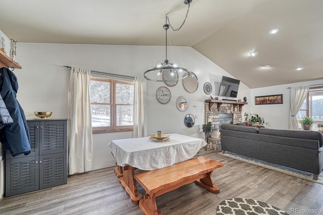 dining room with a fireplace, plenty of natural light, light wood-type flooring, and vaulted ceiling