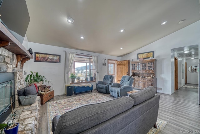 living room with vaulted ceiling, a fireplace, and hardwood / wood-style floors