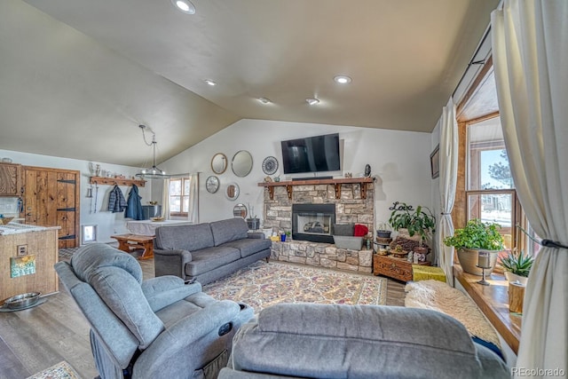 living room featuring vaulted ceiling, a fireplace, and hardwood / wood-style flooring