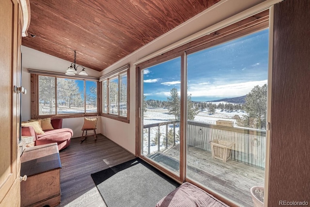 sunroom with a mountain view, lofted ceiling, wood ceiling, and an inviting chandelier