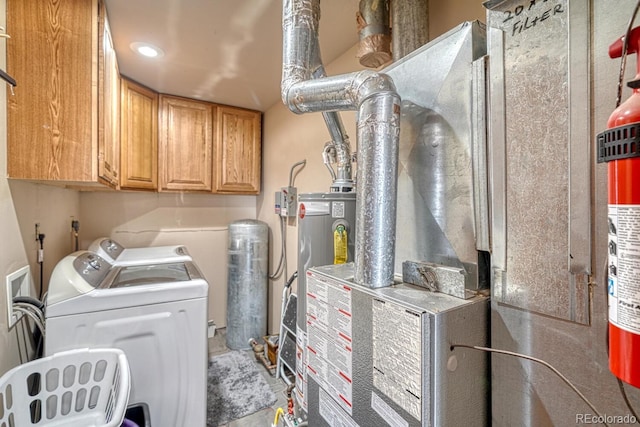 laundry area featuring washer and dryer, cabinets, and water heater