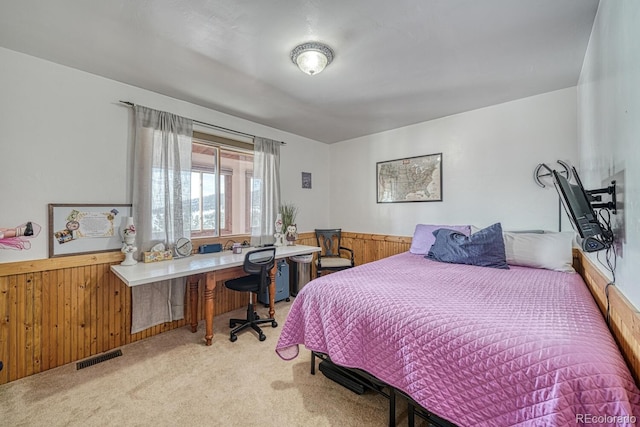 bedroom featuring light carpet and wooden walls