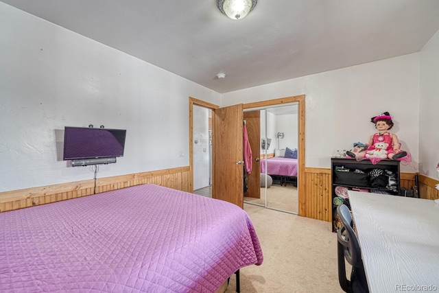 bedroom with light colored carpet, a closet, and wood walls