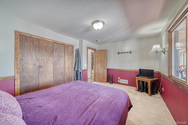 bedroom with multiple windows, a closet, and light carpet