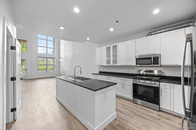 7700 E 29th Ave Unit 102, Denver, CO 80238 - kitchen with stainless steel appliances, a sink, dark countertops, white cabinets, and light wood-style floors