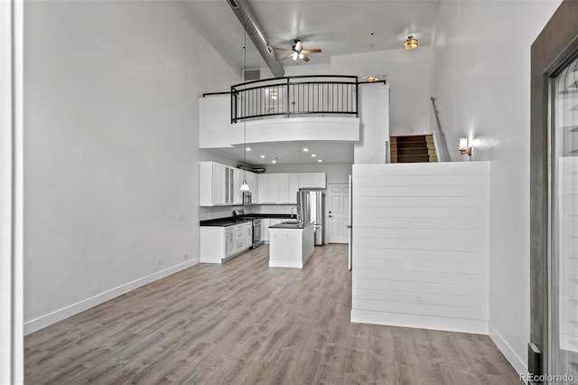 7700 E 29th Ave Unit 102, Denver, CO 80238 - kitchen with open floor plan, appliances with stainless steel finishes, dark countertops, a high ceiling, and a ceiling fan