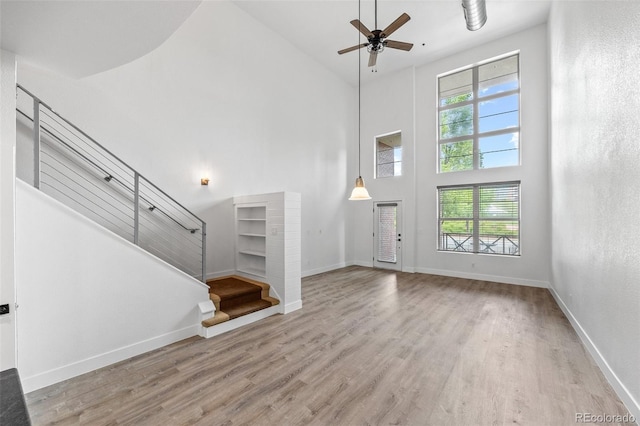 7700 E 29th Ave Unit 102, Denver, CO 80238 - unfurnished living room with a towering ceiling, wood finished floors, ceiling fan, stairs, and healthy amount of natural light