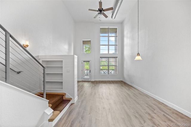 7700 E 29th Ave Unit 102, Denver, CO 80238 - unfurnished living room featuring wood finished floors, plenty of natural light, stairway, baseboards, and a high ceiling