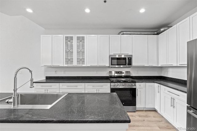 7700 E 29th Ave Unit 102, Denver, CO 80238 - kitchen featuring stainless steel appliances, a sink, white cabinetry, recessed lighting, and glass insert cabinets
