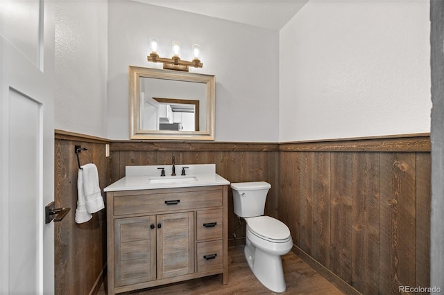 7700 E 29th Ave Unit 102, Denver, CO 80238 - half bathroom with a wainscoted wall, toilet, vanity, and wood finished floors