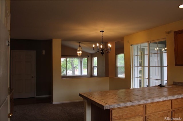 213 Mesa St, Brighton, CO 80601 - kitchen featuring dark colored carpet, a chandelier, baseboards, brown cabinets, and decorative light fixtures