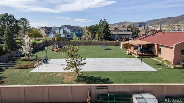 view of yard featuring a mountain view, a patio area, a fenced backyard, and a residential view