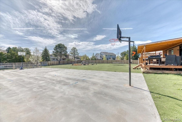 view of sport court with a fenced backyard and a lawn