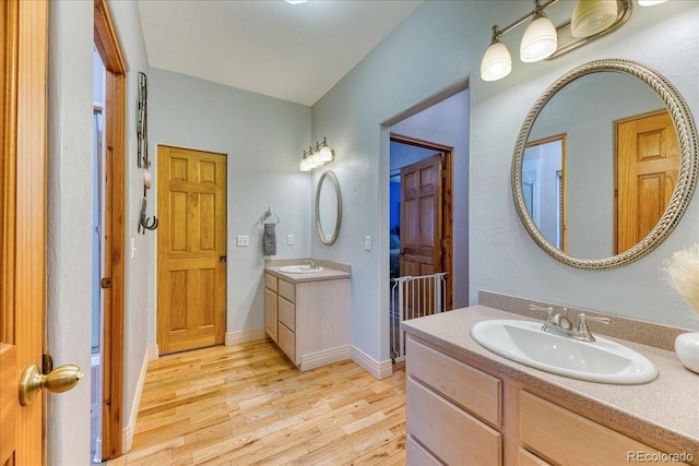 bathroom with a sink, two vanities, and wood finished floors