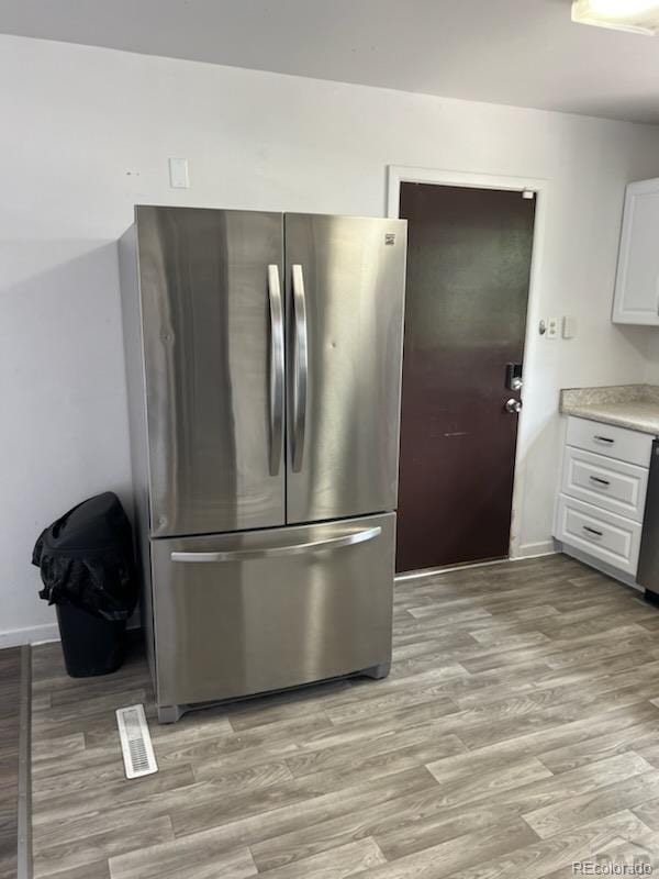 kitchen featuring appliances with stainless steel finishes, white cabinetry, and light hardwood / wood-style flooring