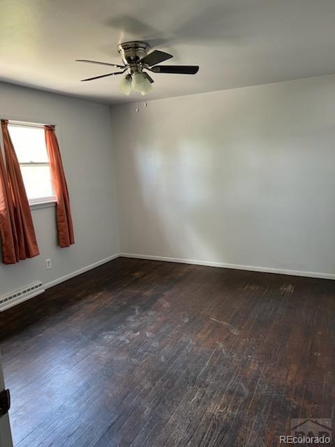 spare room with dark hardwood / wood-style flooring, baseboard heating, and ceiling fan