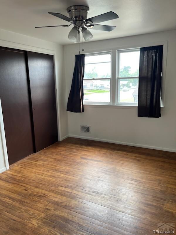 unfurnished bedroom featuring hardwood / wood-style floors, ceiling fan, and a closet