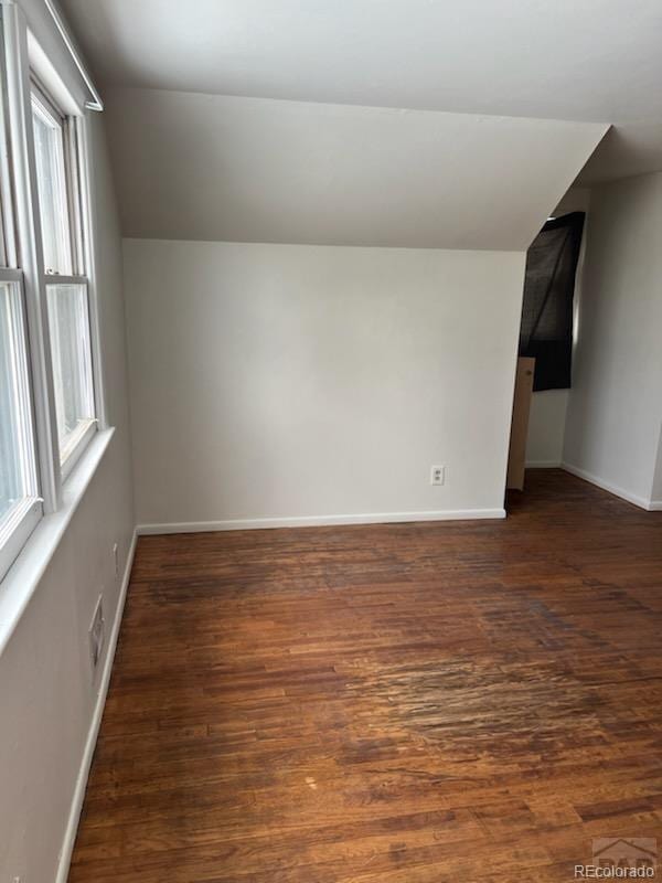 additional living space featuring lofted ceiling, dark hardwood / wood-style floors, and a healthy amount of sunlight