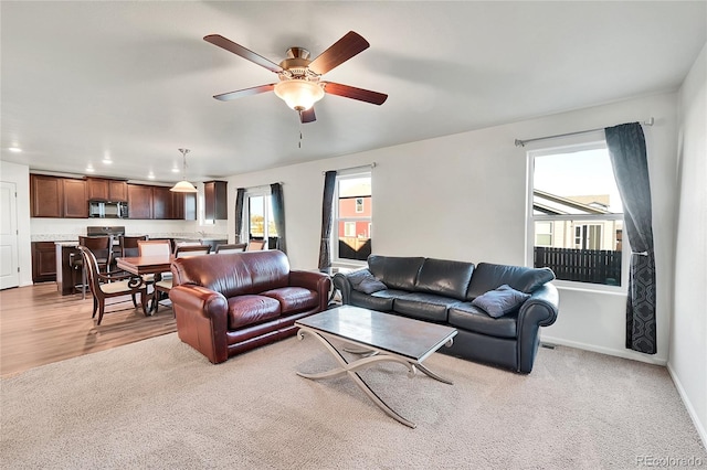 living room featuring plenty of natural light, ceiling fan, and light hardwood / wood-style flooring