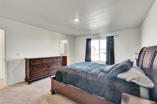 carpeted bedroom with a textured ceiling and connected bathroom