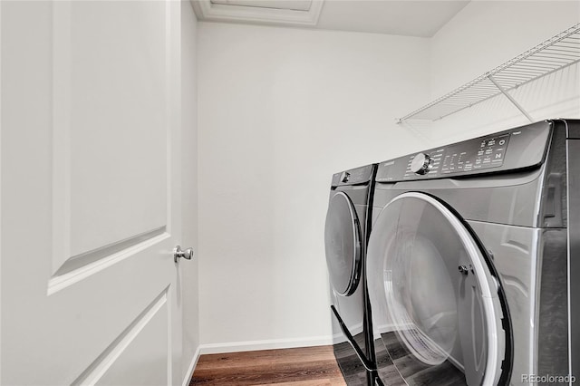 clothes washing area with a wall unit AC, hardwood / wood-style flooring, and independent washer and dryer