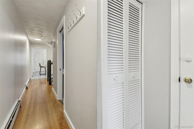 hallway with baseboard heating and light hardwood / wood-style floors