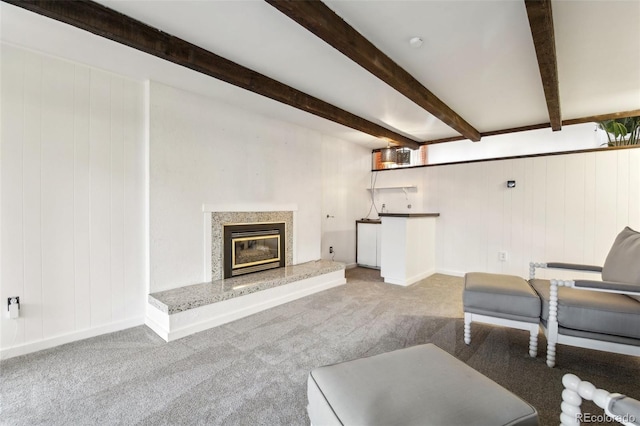 carpeted living room featuring beamed ceiling and a fireplace