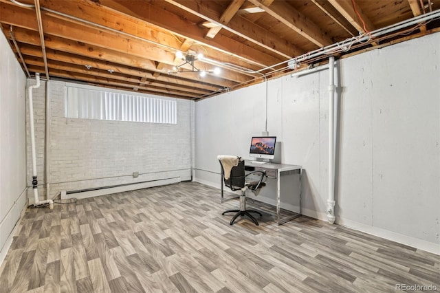 basement with a baseboard radiator, brick wall, and hardwood / wood-style floors