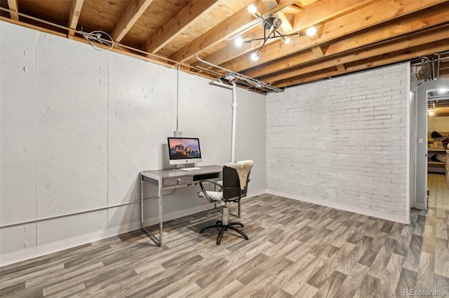 home office with hardwood / wood-style flooring and brick wall