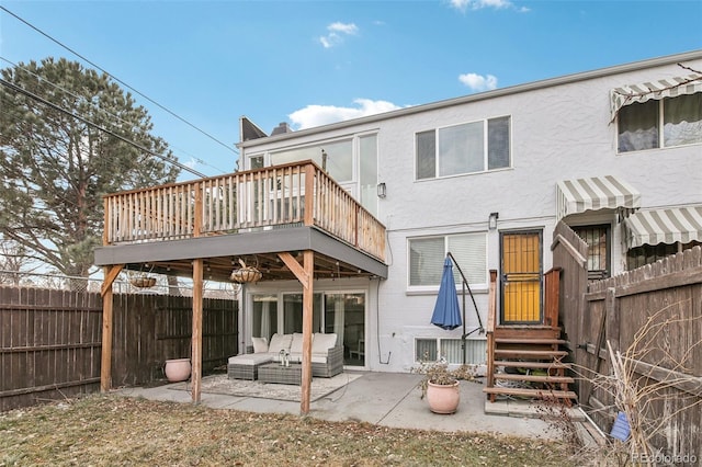 rear view of property featuring a wooden deck, outdoor lounge area, and a patio