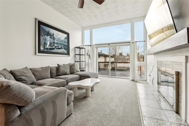 carpeted living room featuring a tile fireplace, floor to ceiling windows, and ceiling fan