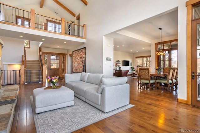 living area featuring beam ceiling, a healthy amount of sunlight, and wood-type flooring