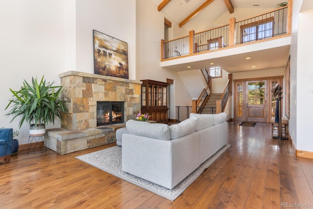 living room featuring stairs, beamed ceiling, baseboards, and hardwood / wood-style flooring