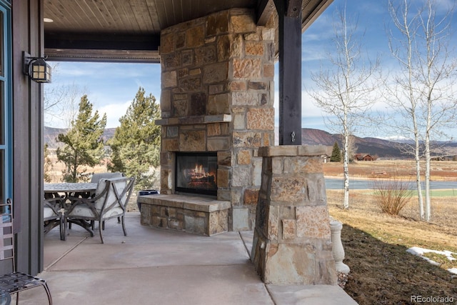 view of patio / terrace featuring an outdoor stone fireplace and a mountain view