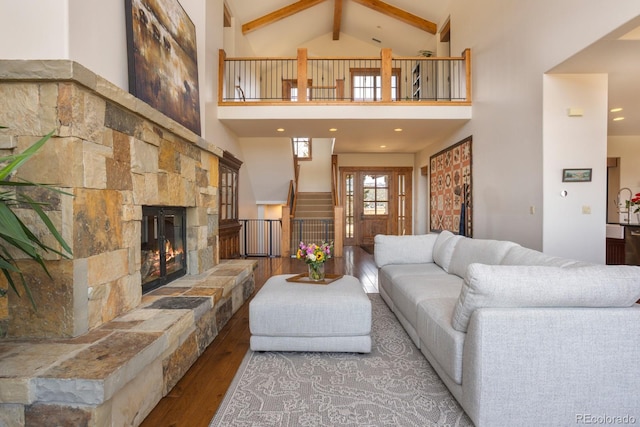 living area with a stone fireplace, beamed ceiling, high vaulted ceiling, and hardwood / wood-style flooring
