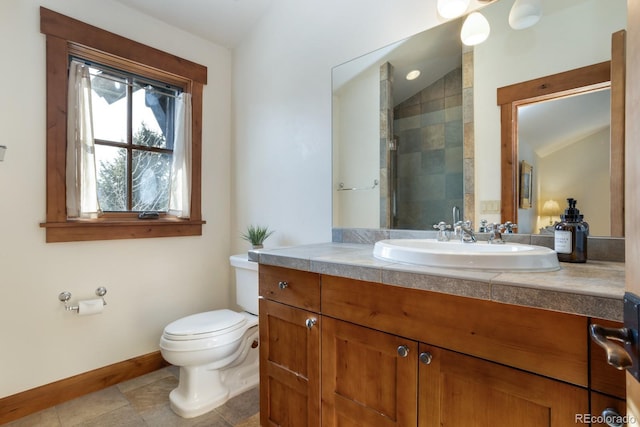 bathroom featuring baseboards, toilet, vanity, tiled shower, and vaulted ceiling