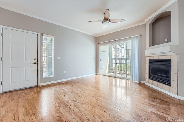 unfurnished living room with a tiled fireplace, ornamental molding, light hardwood / wood-style flooring, and a wealth of natural light