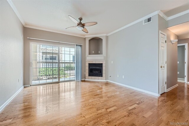 unfurnished living room with ornamental molding, light hardwood / wood-style flooring, a tile fireplace, and ceiling fan