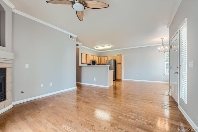 unfurnished living room featuring light hardwood / wood-style floors, ornamental molding, a tile fireplace, and ceiling fan with notable chandelier