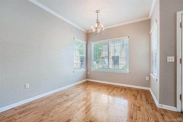 spare room featuring a notable chandelier, crown molding, and light wood-type flooring