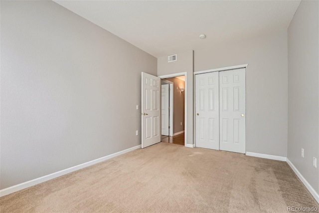 unfurnished bedroom with light carpet and a closet