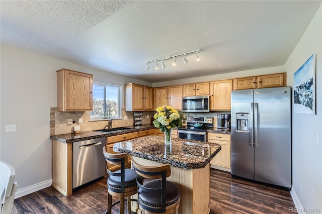 kitchen featuring dark wood finished floors, decorative backsplash, appliances with stainless steel finishes, a sink, and baseboards